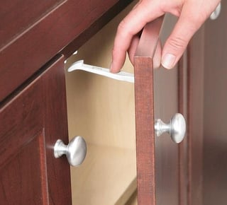 To disengage a safety latch, open the cabinet door and press down on the locking tab.