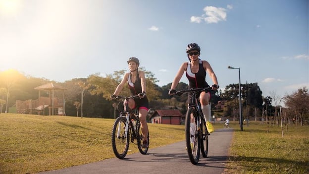 two women riding bikes on a paved road related post image