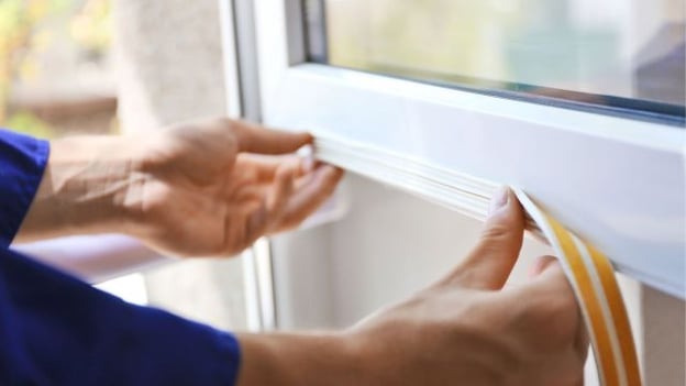 person applying weather stripping at home
