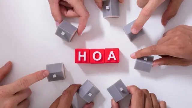 HOA sign surrounded by people holding tiny houses