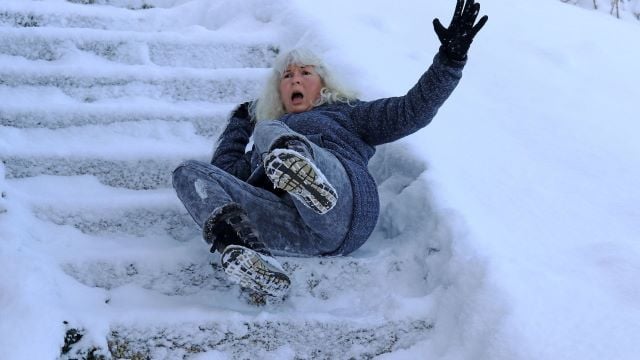 Woman slipping down snow-covered stairs